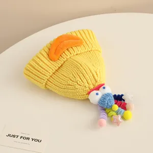 Detailed shot of yellow knitted baby hat with orange duck beak and colorful crochet accents