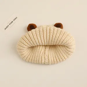 Dettaglio del cappello in maglia beige per neonato con orecchie da orso e trama spessa