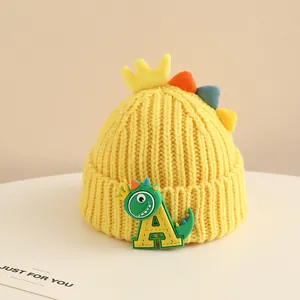 Close-up of yellow knit baby hat with cartoon dinosaur and letter A embroidery