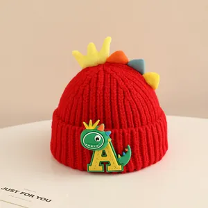 Detail of red knit hat showing soft wool texture and colorful 3D dinosaur spikes