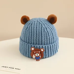 Dettaglio berretto neonato in maglia blu con orecchie da orso e patch in silicone