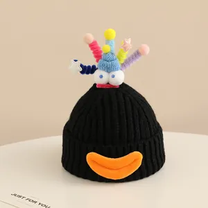 Close-up of black knitted winter hat with colorful pom-poms and funny cartoon eyes