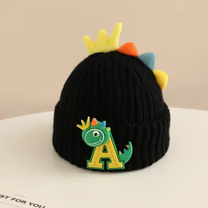 Detailed close-up of children's black knit hat with 3D crown and dinosaur patch