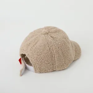 Detail of warm beige teddy fleece baseball cap with adjustable Velcro strap and smile tag