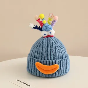 Close-up of blue knit hat with cartoon big eyes, orange mouth, and colorful spiral details