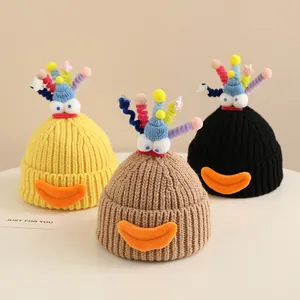 Three kids' winter knit beanies in yellow, brown, and black with funny snowman eye decorations