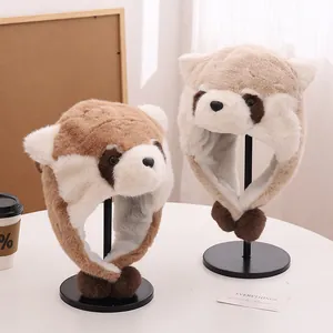 Close-up of plush raccoon winter hats with fuzzy ears and pom-poms on a white table