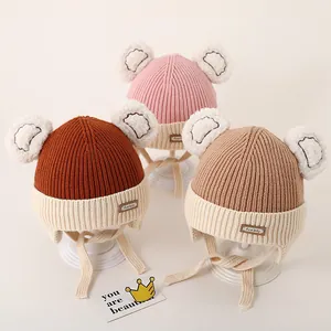 Detailed view of knitted baby hats with bear ears and earflaps in three soft colors