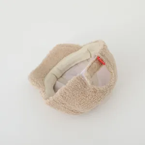 Detail of adjustable velcro strap and red CUTE label on beige fleece winter hat