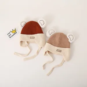 Close-up of baby winter knit hats with cute bear ears and protective earflaps in warm tones