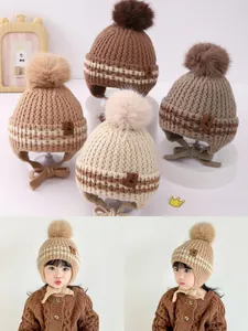 Detail of knit baby aviator hat with pom-pom and adjustable chin strap in earth tones