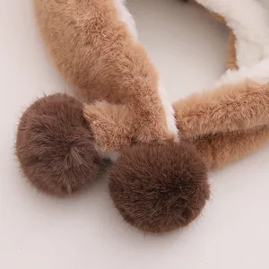 Close-up of soft plush winter hat fabric featuring two dark brown fluffy pom-poms details