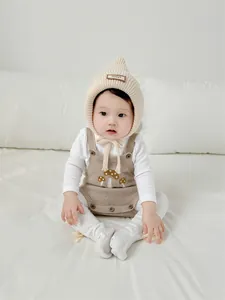 Detail of baby knit pointed witch hat and mushroom pattern romper in soft cream
