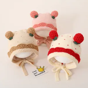Details van gebreide babymutsen met aardbeien in roze en beige met golvende randen