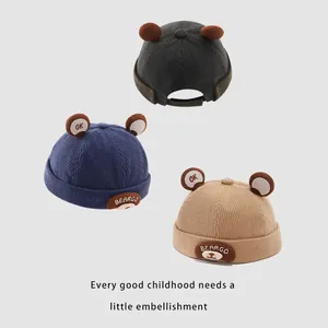 Three corduroy toddler beanies with plush ears and bear patches in blue, khaki and grey