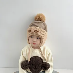 Detail of children's knit trapper hat in khaki and brown with soft faux fur pompom