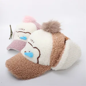 Dettaglio di cappelli invernali rosa e marroni con ricamo a orso e pom pon
