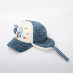 Detail of blue dinosaur embroidery and fluffy lamb wool texture on kids winter trapper hat