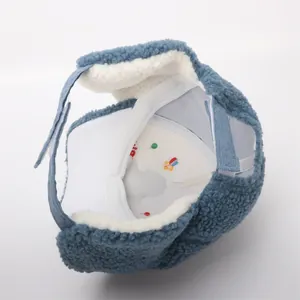 Detailed close-up of blue dinosaur baby winter hat lining with soft white fleece and embroidery