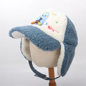 Detail of blue and white plush dinosaur earflap hat with airplane patch and Biu embroidery