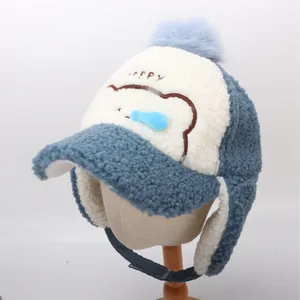 Dettaglio del cappello aviatore in pile sherpa blu con pompon e ricamo HAPPY per bambini