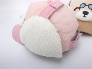 Dettaglio cappello invernale rosa con paraorecchie in pile bianco e texture trapuntata