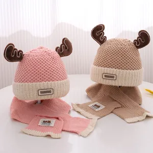 Warme gebreide babymuts en sjaal set met rendiergewei in zacht roze en beige