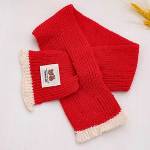 Detail van rood en crème gebreide sjaal met Fashion Kids-patch op marmer