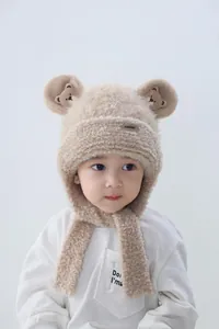Close-up of beige fleece hat showing soft texture, teddy ears and bear embroidery detail