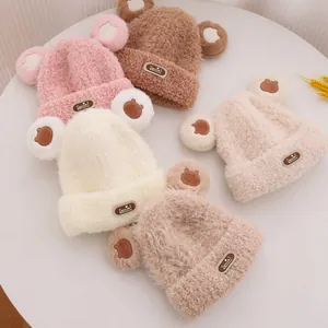 Vista piatta di cappelli in pile con orecchie da orso, ricami e etichette in pelle