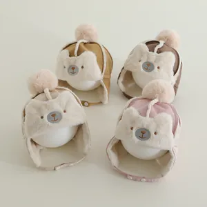 Detail showing plush earflap winter hats for babies with bear embroidery and pom poms