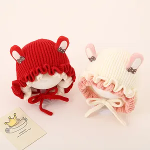 Detail of baby knitted hats with rabbit ears, bow accents and scalloped edges