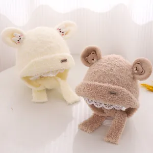 Detail of plush baby beanies with ear flaps, lace trim, and soft teddy bear design