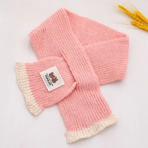 Detail van roze gebreide kindersjaal met zachte pluche rand en cartoon-dierenpatch