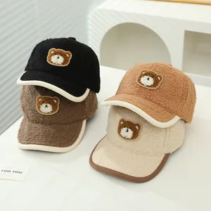 Dettaglio di quattro cappellini in lana di agnello con patch di orso in nero, caffè e cammello
