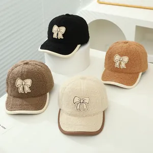 Close-up of winter faux shearling baseball caps featuring delicate bow details and trim