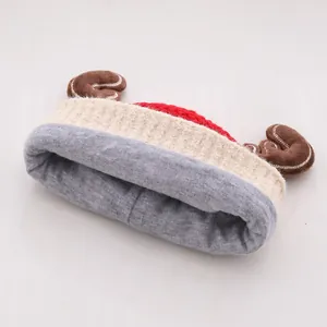Detail van rode gebreide babymuts met pluchen rendiergewei en zachte witte fleece voering
