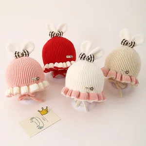 Détail de bonnets tricotés pour bébé avec oreilles de lapin et nœuds en quatre coloris