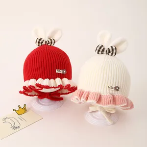 Détail de bonnets tricotés pour bébé avec oreilles de lapin et nœud rayé rouge et blanc