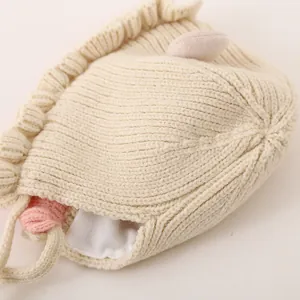 Detailed close-up of baby knit hat showing soft beige ribbed texture and plush bunny ear