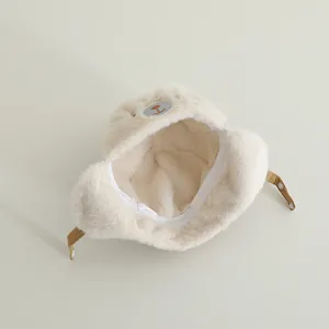 Detailed view of plush baby trapper hat with bear embroidery and snap-on chin straps