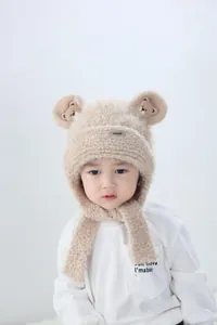 Detail of plush bear ear hat showing soft beige faux fleece texture and ear flaps