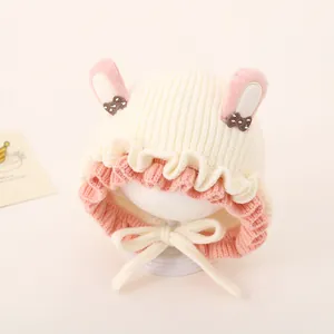Detail of baby knit hat with pink bunny ears and soft white yarn texture closeup