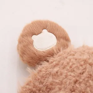 Dettaglio macro del cappello invernale marrone felpato con toppa ricamata a forma di orso