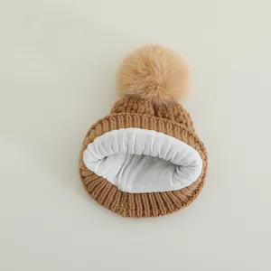 Winter knit hat for kids in brown featuring a fluffy pom pom and warm fleece lining