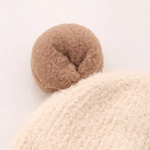 Gros plan du bonnet en tricot ours en peluche montrant la texture douce du mouton beige