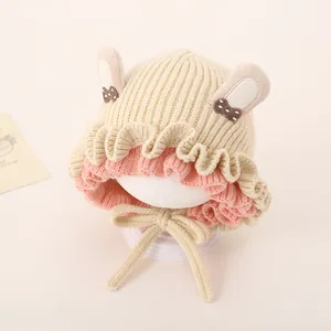 Detail of cream knit baby hat featuring cute rabbit ears and decorative polka dot bows