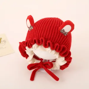 Detail of red baby knit hat with 3D bunny ears and brown polka dot bow decoration