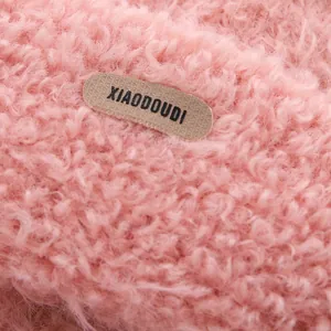 Close-up of soft pink plush fabric detail with leather brand label on kids winter hat