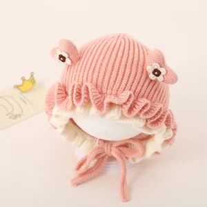Detail of pink knitted baby hat with cute 3D ears and wavy frill edges for winter warmth